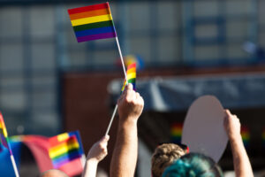 crowd waving rainbow flags at pride parade