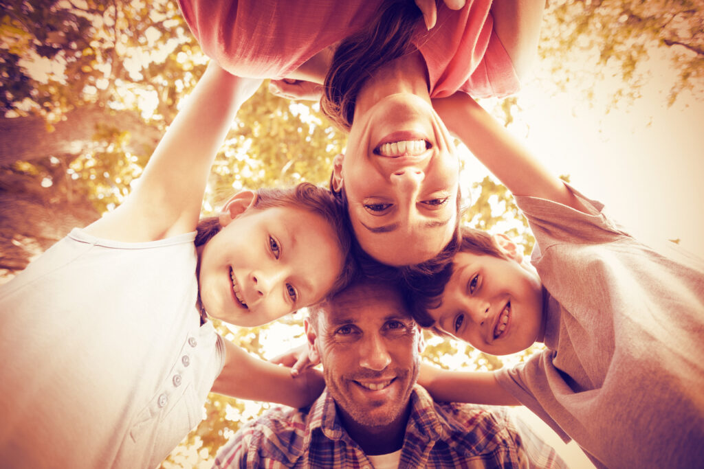 Portrait of happy family in park huddling in circle