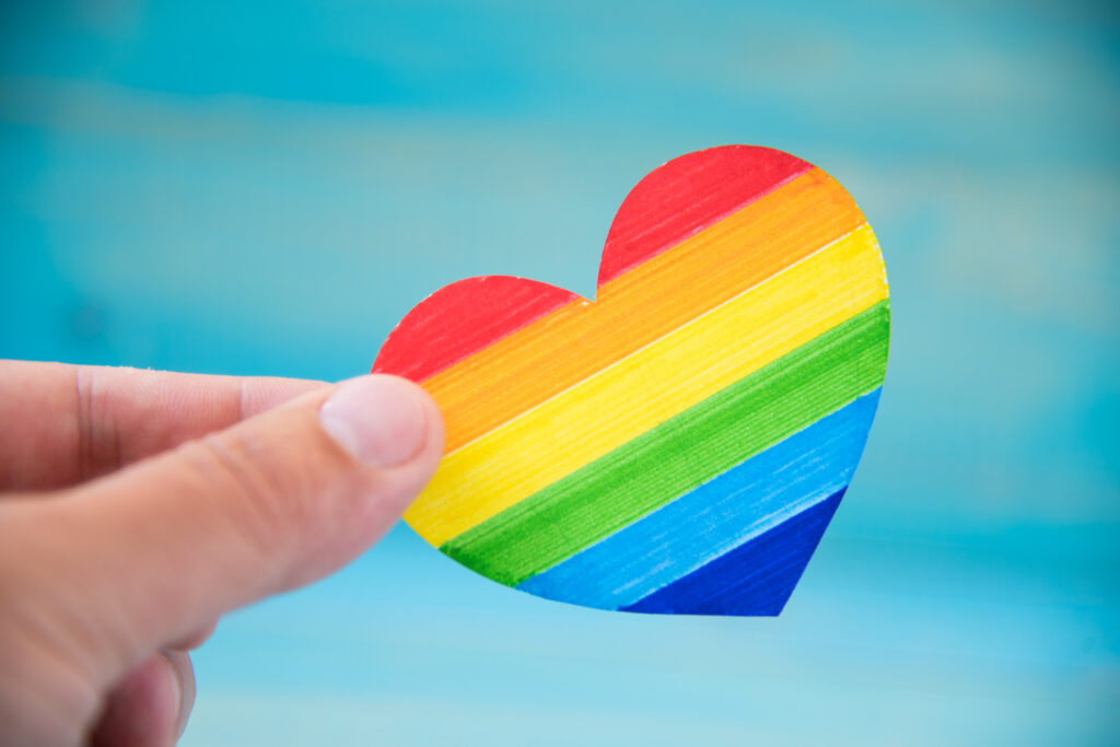 LGBT concept. Hand on blue background holding heart rainbow colors