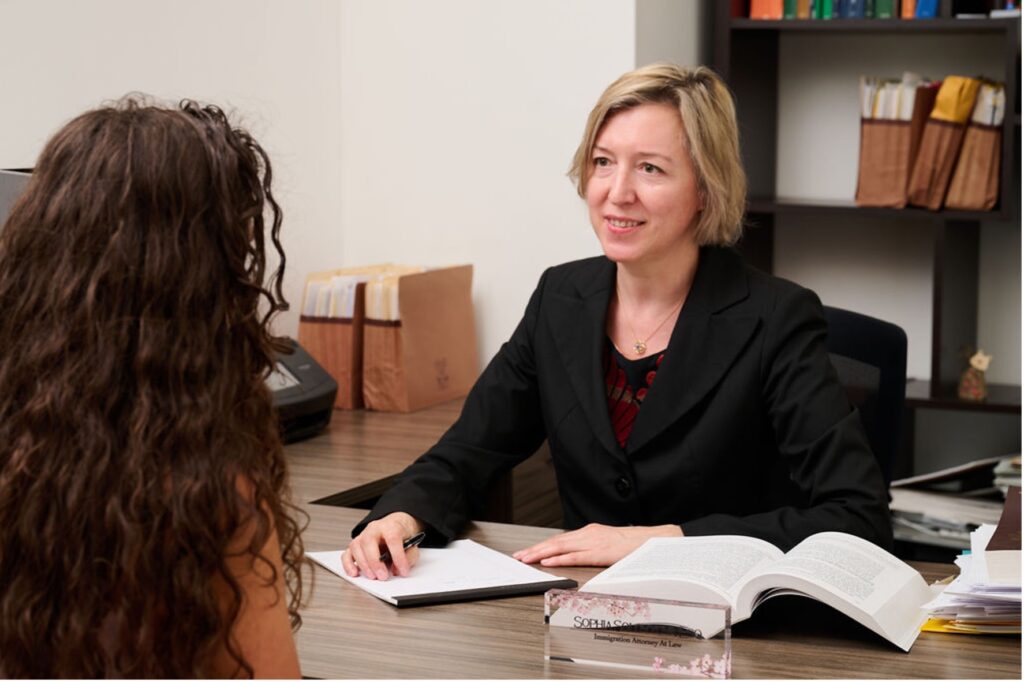 Immigration attorney Sophia Solovyova meeting with a client in her office, discussing legal documents.